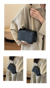 Close-up of black quilted shoulder bag featuring V-shaped stitching and gold chain strap