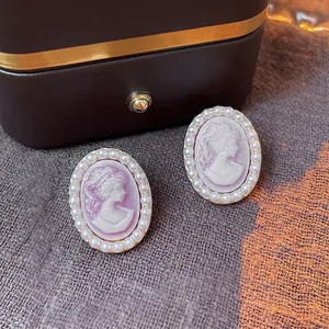 French vintage cameo earrings with purple portrait and pearl borders on jewelry box
