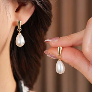 Macro view of French vintage drop pearl earrings with elegant gold-tone metal hooks