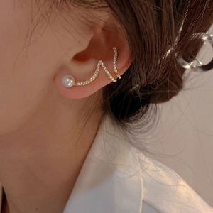 Detailed view of elegant wavy gold ear cuff with small diamonds and round white pearl