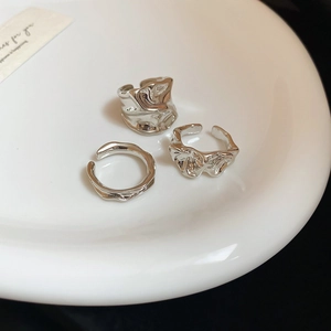 Detail view of three-piece silver lava textured irregular rings in a ceramic dish