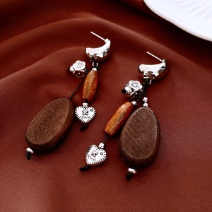 Close-up of vintage wood beaded earrings with silver needle and engraved heart charms