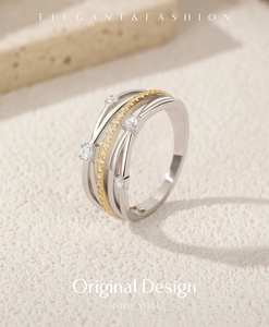 Close-up of S925 silver and gold crossover ring with sparkling crystals on textured background