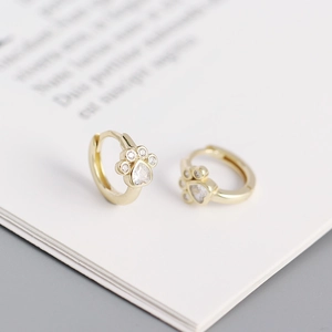 Macro shot of gold cat paw earrings with white cubic zirconia heart-shaped stones