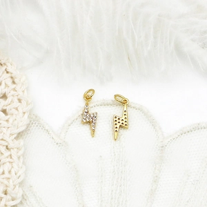 Macro view of 18K gold plated lightning bolt pendants with cubic zirconia on lace