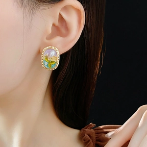 Detailansicht ovaler goldener Vintage-Ohrringe mit bunter Blumenemaille an einem Model