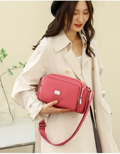 Detalle del bolso bandolera de nylon rosa con correa ajustable y bolsillos con cremallera