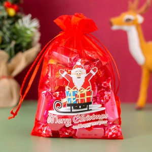 Close-up of red organza Christmas gift bag with Santa print and Merry Christmas text