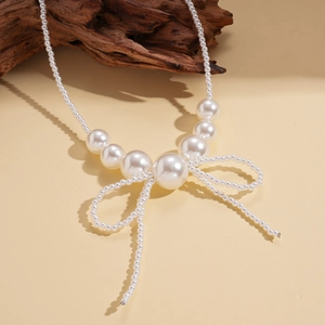 Elegant faux pearl necklace with bow pendant design over a minimalist background