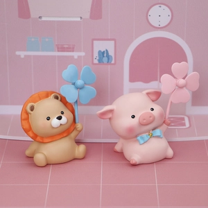 Close-up of cute resin lion and pig figurines holding colorful clovers for car decor