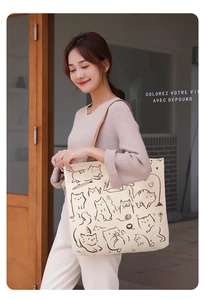 Minimalist canvas tote bag featuring a brown cat illustration worn by a model in a cozy setting
