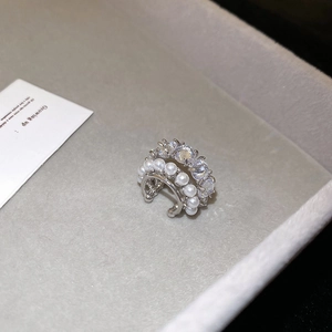 Macro shot of silver zircon flower ear cuff with white pearls on a grey velvet tray