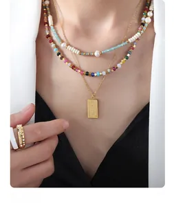 Close-up of layered colorful tourmaline bead necklaces with pearl and engraved pendant