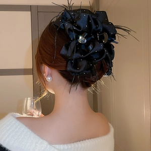 Détail d'une grande pince à cheveux fleur noire avec plumes et cristal en forme de cœur