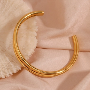 Detailed view of an 18K gold plated double-layer open bangle on elegant silk fabric
