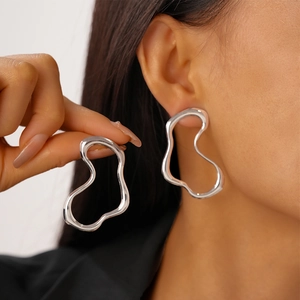 Minimalist silver irregular wave hollow earrings with a polished metallic finish on model