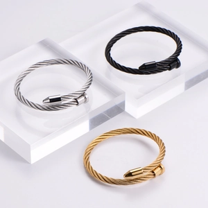Detailed view of three twisted cable bracelets in silver, black, and gold stainless steel