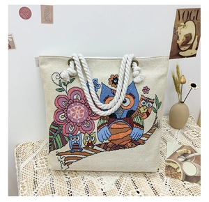Detail of bohemian canvas tote bag with colorful owl floral embroidery and cotton rope handles