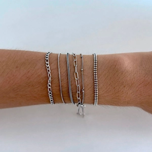 Macro shot of silver-plated stainless steel multi-chain bracelet set on a person's wrist