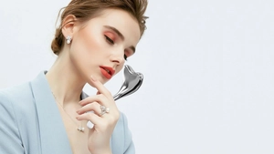 Close-up of a silver mermaid heart-shaped facial ice globe massager used on the cheek