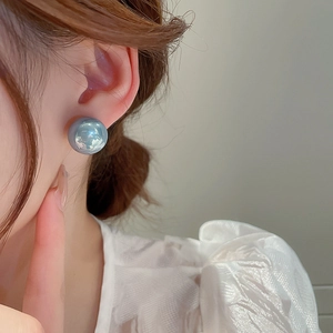 Close-up of grey-blue round pearl stud earring worn by a model in a minimalist style