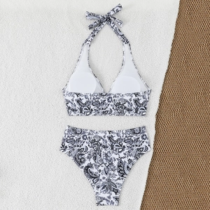 Detailed flat lay of black and white paisley bikini set on a beach-style straw mat