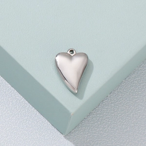 Titanium steel heart pendant necklace in silver finish on a green geometric block