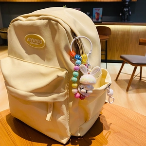 Cute white cartoon rabbit keychain with colorful beads on a yellow fashion backpack