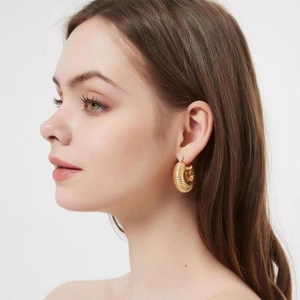 Detail of chunky golden hoop earrings with fine horizontal thread texture and vintage finish