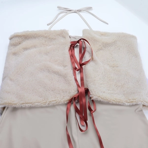 Dettaglio dell'abito beige con spalle scoperte, bordo in ecopelliccia e lacci marroni
