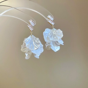 Macro detail of cascading white petal tassels and zircon accents on floral drop earrings