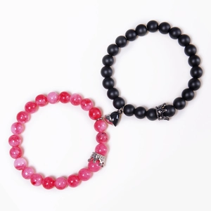 Close-up of heart-shaped magnetic clasp and crown charms on beaded couple bracelets