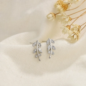 Detailed macro shot of s925 silver leaf earrings with marquise cut stones on linen