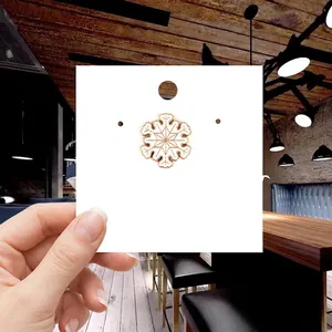 Detailed view of a gold and white enamel snowflake brooch pinned on a display card
