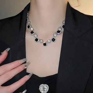 Detail of silver necklace with black round stones worn on neck in premium lighting