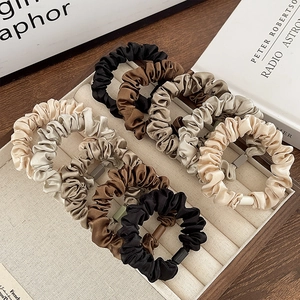 Silky satin scrunchies in assorted neutral tones displayed on a premium jewelry tray