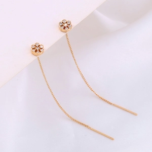 Macro detail of golden snowflake earrings with sparkling zircons and long tassels