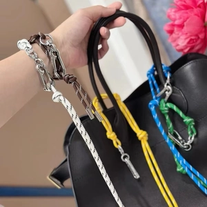 Gekleurde gevlochten touw tasbedels met metalen sluiting op een zwarte handtas