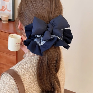 Close-up of navy blue and checkered fabric bow hair tie worn on a high ponytail