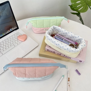 Detailed view of quilted pencil cases in pastel colors with floral lining and zipper