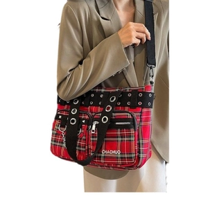 Red plaid punk tote bag with rivet details and black crossbody strap on model