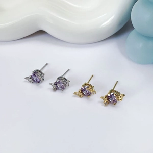 Macro shot of 18k gold and silver star earrings with purple zircon and wing details