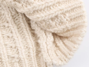 Makroaufnahme des cremefarbenen Strickpullovers mit strukturiertem Zopfmuster