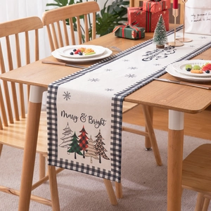 Modern Christmas table runner with festive tree prints and black plaid border on wood table