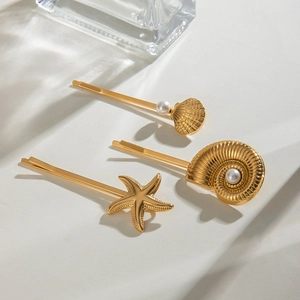 Detailed view of gold starfish and shell hair clips with pearls on a minimal surface