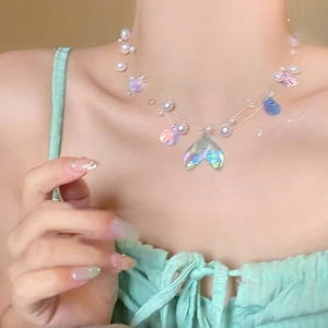 Detail of iridescent mermaid tail pendant with white pearls on a minimalist necklace