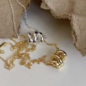 Macro shot of S925 sterling silver necklaces featuring intertwined rings in gold and silver