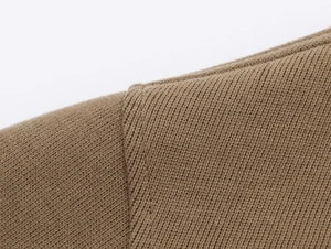 Close-up of shoulder seam detail on brown knit hoodie showing high-quality stitching