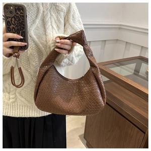 Detail of a brown woven hobo bag featuring a knotted handle and soft leather texture