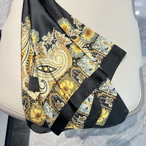 Détail d'un foulard satiné à motifs paisley dorés sur un siège en cuir